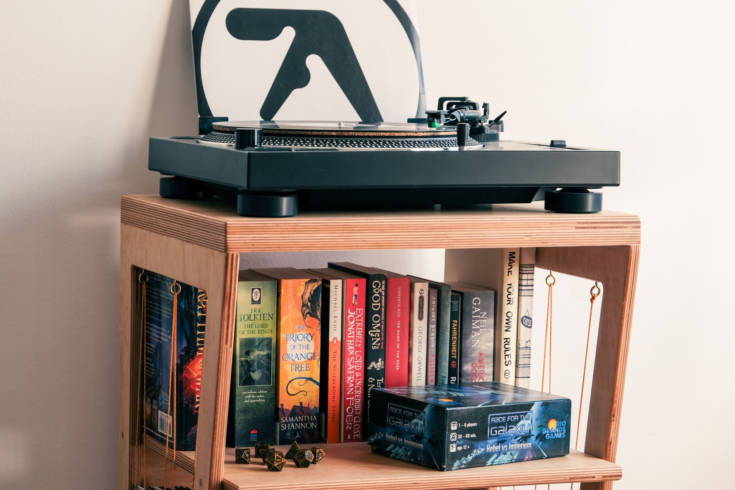 A turntable on a wooden bookshelf filled with books.